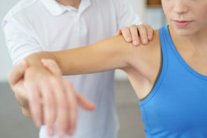 Bowen therapist treating female clients shoulder in seated position